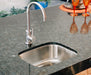 Stono Outdoor Living The TrueFlame 19" x 15" Stainless Steel Undermount Sink (TF-NK-19U) features a modern design with a curved faucet, set in polished dark granite. Orange glassware and a centerpiece in the background add charm—ideal for any outdoor kitchen.