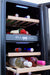Stono Outdoor Living A close-up of the TrueFlame 15" 3.2 Cu. Ft. Outdoor Rated Dual Zone Wine Cooler (AMD-RFR-15WD) in an outdoor kitchen, with wooden shelves storing wine, strawberries, and cheese, plus digital controls and interior lighting.