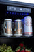 Stono Outdoor Living Several cans of Yeti Imperial Stout and one Modern Times beer, along with green grapes and strawberries, are stored in a TrueFlame 15" Outdoor Rated Refrigerator. Blue LED lights and a digital temperature display illuminate the fridge’s stainless interior.