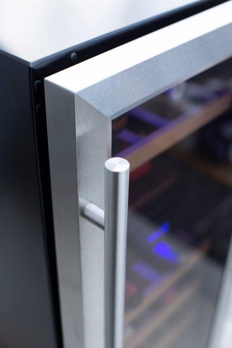 Stono Outdoor Living Close-up of a slightly open TrueFlame 15" 3.2 Cu. Ft. Outdoor Rated Dual Zone Wine Cooler (AMD-RFR-15WD), showing its metal handle, glass door, shelves, and blue interior light—ideal for outdoor refrigeration needs from TrueFlame.