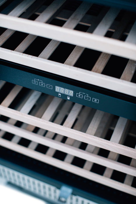 Stono Outdoor Living Close-up of empty wooden shelves inside the TrueFlame 24" 5.3 Cu. Ft. Outdoor Rated Dual Zone Wine Cooler—features stainless steel design, digital controls, and is perfect for outdoor kitchens or refrigeration by TrueFlame.