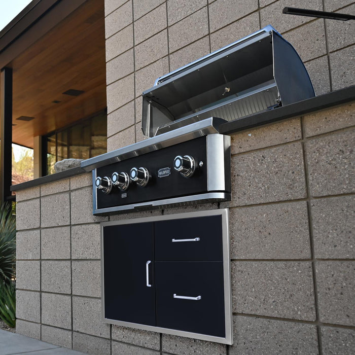 Stono Outdoor Living A Wildfire Outdoor Living Ranch Pro 36-in 3 Burner Black 304 SS Natural Gas Grill (WFPRO36G-BSS-NG) with an open hood is built into a modern stone patio above two black cabinet doors with silver handles for a sleek, contemporary look.