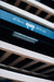 Stono Outdoor Living Close-up of wooden shelves and softly focused horizontal slats inside the TrueFlame 24" 5.3 Cu. Ft. Outdoor Rated Dual Zone Wine Cooler, shown with its digital control panel.