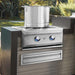 Stono Outdoor Living A large stainless steel pot sits on the Twin Eagles Built-In Natural Gas Power Burner (TEPB24HG-CN) with two blue-lit knobs and a reversible heavy-duty grate, set in a modern patio kitchen against greenery.