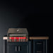 Stono Outdoor Living The TrueFlame 32" 4-Burner Built-In Propane Gas Grill (TF32L) features four illuminated control knobs, set in a sleek outdoor kitchen against a dark, minimally lit backdrop.