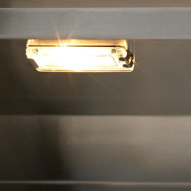 Stono Outdoor Living A close-up of a small rectangular light fixture mounted under a shelf in an outdoor kitchen, casting a warm yellow glow on the surface below—ideal for nights by your Delta Heat 38-Inch 3-Burner Built-In Natural Gas Grill (DHBQ38G-DN).