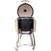Stono Outdoor Living The Coyote Asado Smoker w/ Stand & Side Shelves (C1CHCS-FS) by Coyote is a black kamado-style charcoal grill with a domed lid, wooden side shelves, sturdy metal frame, and wheels for easy outdoor cooking—shown on a white background.