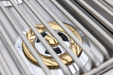Stono Outdoor Living Close-up of the Blaze Premium LTE+ Natural Gas Stainless Steel Double Side Burner w/ Lid (BLZ-SB2-LTE3-NG) by Blaze, featuring sleek brass and silver components under parallel grates—ideal for a clean, modern outdoor kitchen.