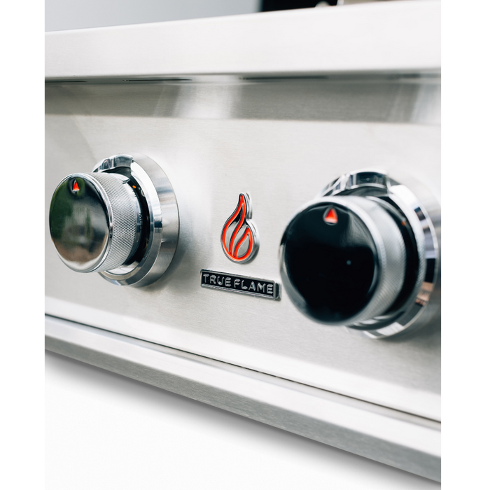 Stono Outdoor Living Close-up of two control knobs on the TrueFlame E Series 25" Stainless Steel 3-Burner Built-In Propane Gas Grill (TFE25L), featuring a red flame logo and the TrueFlame brand name between the knobs.