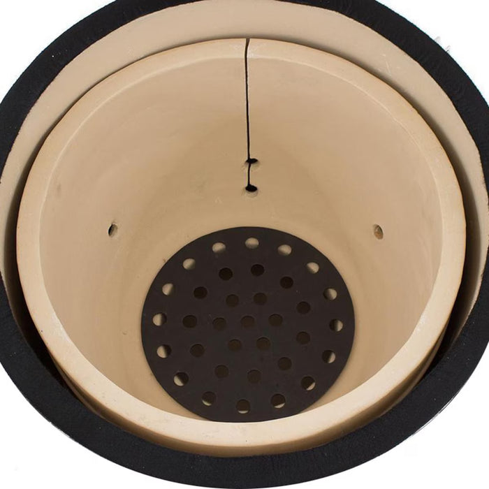 Stono Outdoor Living A close-up of the Coyote Asado Smoker, Built-In - C1CHCS by Coyote shows its beige ceramic interior, black inner ring, round perforated drainage plate, and a visible crack—features for precise temperature control.