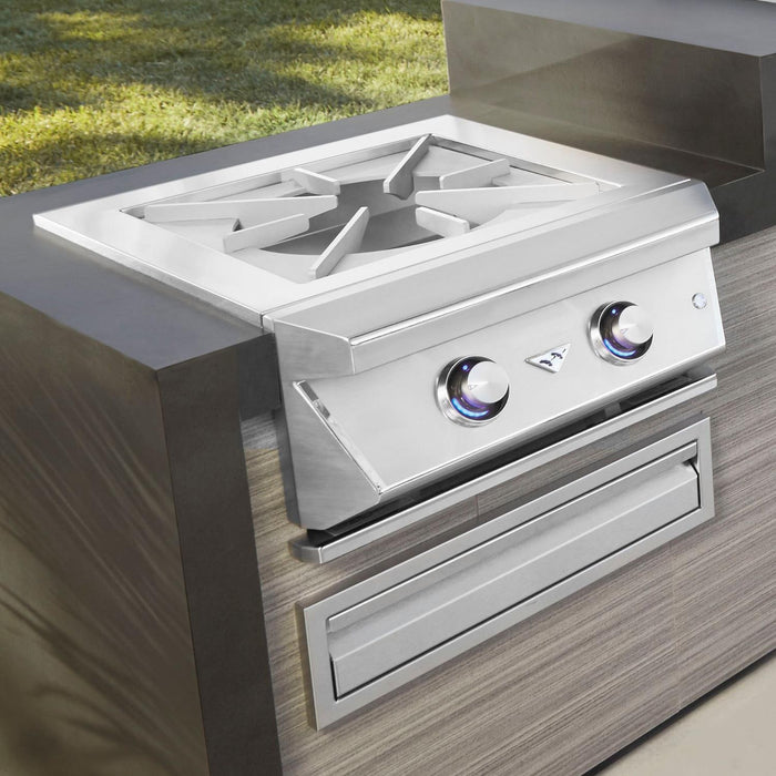 Stono Outdoor Living The Twin Eagles Built-In Propane Gas Power Burner (TEPB24HG-CL) features a reversible heavy-duty grate, stainless steel lid, and two control knobs, installed in a wood-textured counter with grass in the background.