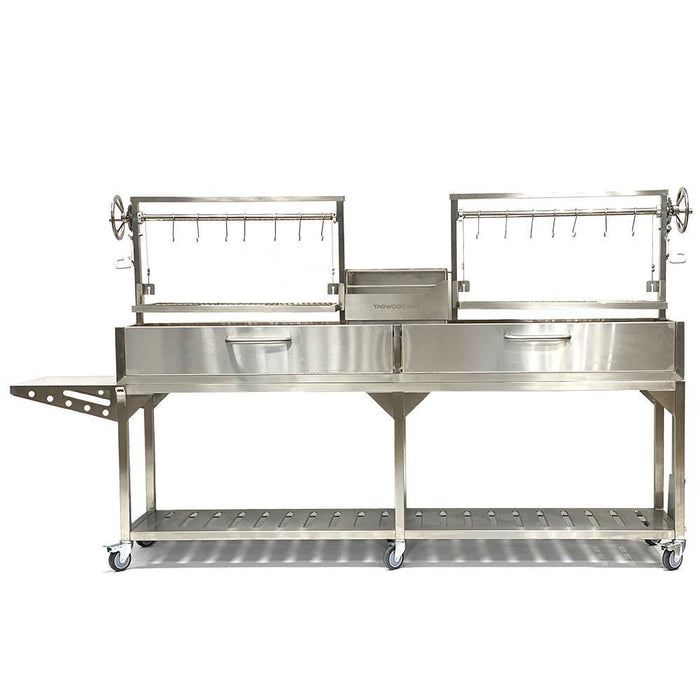 Stono Outdoor Living The Tagwood BBQ Double Argentine Santa Maria Wood Fire & Charcoal Grill (BBQ04SS) by Tagwood BBQ is a large stainless steel grill with two grilling areas, rotating spits, hanging hooks, side and lower shelves, and wheels for easy mobility.