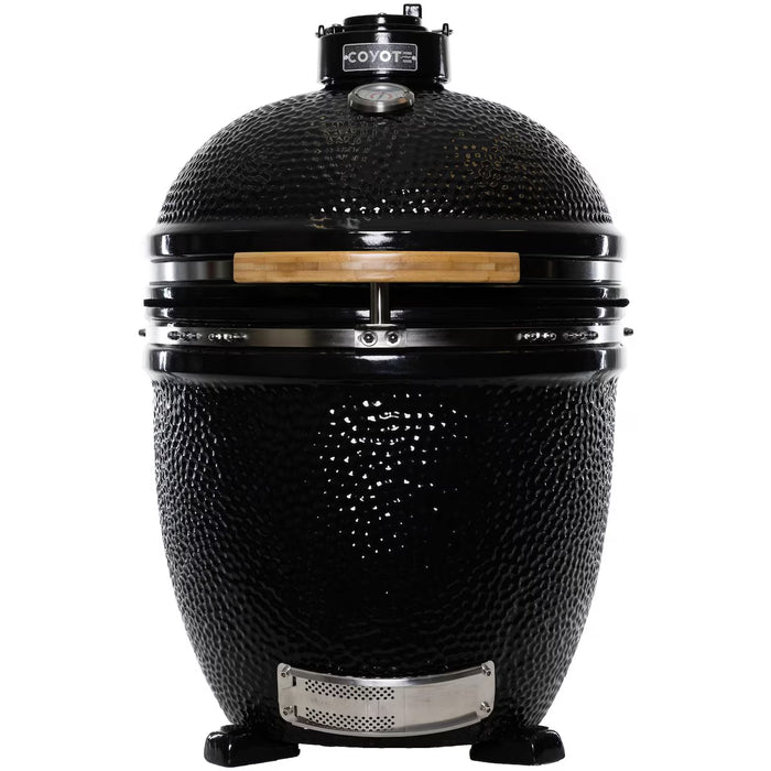 Stono Outdoor Living The Coyote Asado Smoker, Built-In (C1CHCS), is a black ceramic kamado-style charcoal grill with a domed lid, wooden handle, temperature gauge, and air vents on sturdy legs—ideal for outdoor cooking.