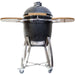 Stono Outdoor Living The Coyote Asado Smoker w/ Stand & Side Shelves (C1CHCS-FS) is a black ceramic kamado-style charcoal grill with a domed lid, wooden shelves, stainless steel legs, and wheels—ideal for outdoor cooking and shown on a white background.