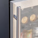 Stono Outdoor Living Close-up of the stainless steel handle on the TrueFlame 24" 5.1 Cu. Ft. Outdoor Rated Refrigerator (AMD-RFR-24G) by TrueFlame, with several cans of beverages visible inside through the glass door.