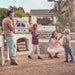 Stono Outdoor Living A family of four enjoys pizza outdoors by their modern backyard kitchen featuring the Delta Heat 30-Inch Built-In Pizza Oven (Propane, DHPO30BI-L) as they smile and spend time together on a sunny day.
