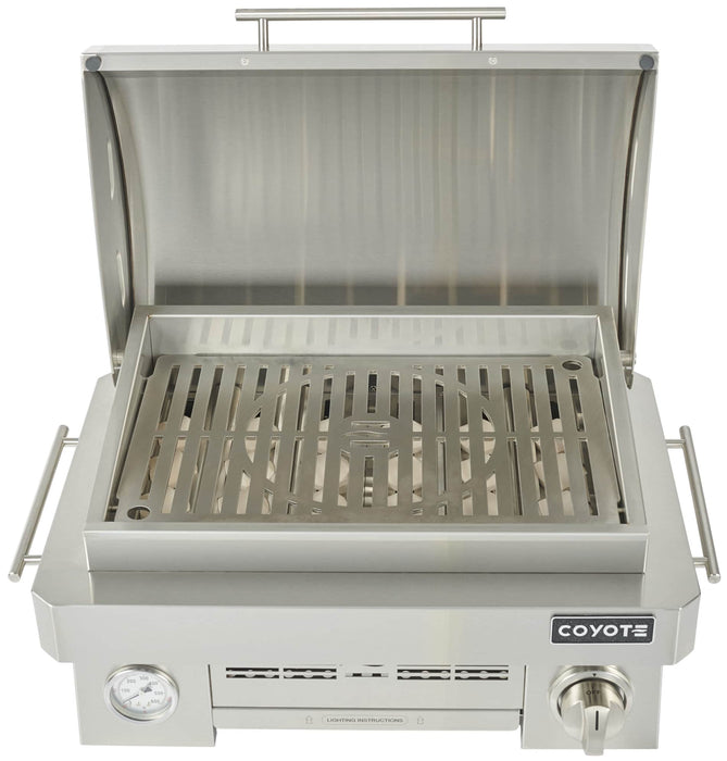 Stono Outdoor Living A Coyote 25" Portable Grill (C1PORTLP) by Coyote, featuring a single ceramic burner, temperature gauge, control knob, and marine-grade stainless steel construction, shown from above with the lid open.