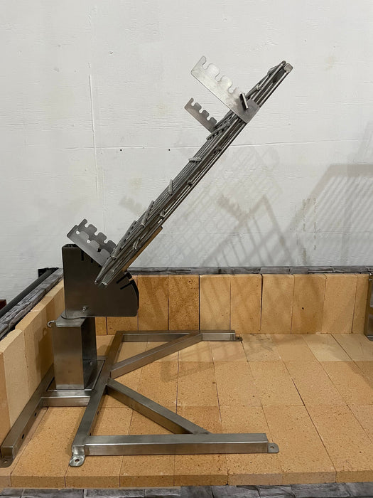Stono Outdoor Living The Tagwood BBQ Basement Grill - BBQ94SS by Tagwood BBQ features an SS 304 clamp grill rack with angled slots, mounted on a sturdy frame and set on light-colored bricks in a basement against a plain white wall. The rack is designed to hold items at an angle.
