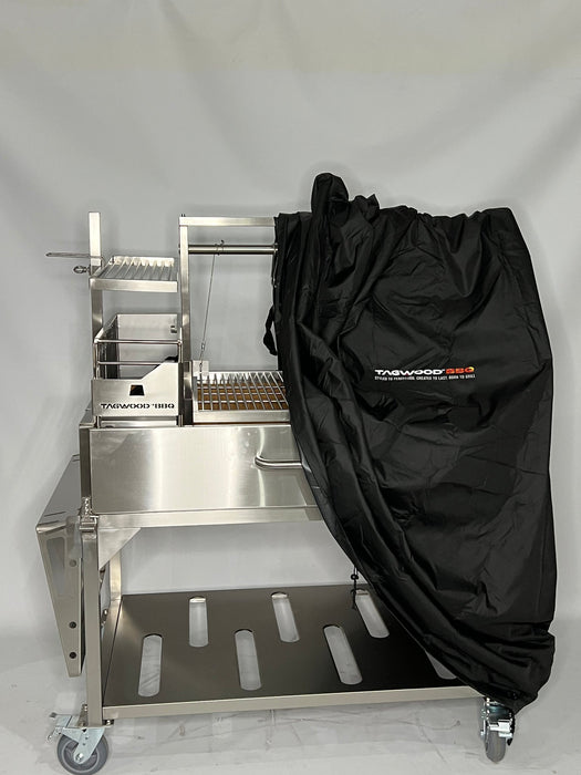 Stono Outdoor Living A Tagwood BBQ Grill Cover for BBQ23SS Grill - BBQ86SS, black and water-resistant, partially covers a stainless steel outdoor grill with shelving and accessories on wheels. The Tagwood BBQ logo is visible against a plain light background.