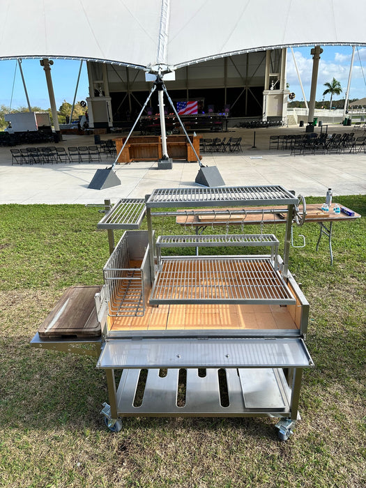 Stono Outdoor Living The Tagwood BBQ Round Warming Roof Grill for BBQ03SS/BBQ05SS - BBQ92SS features multiple cooking grates, a warming rack, and wooden cutting boards. This 304 stainless steel Argentine-style grill is on wheels for easy outdoor use.