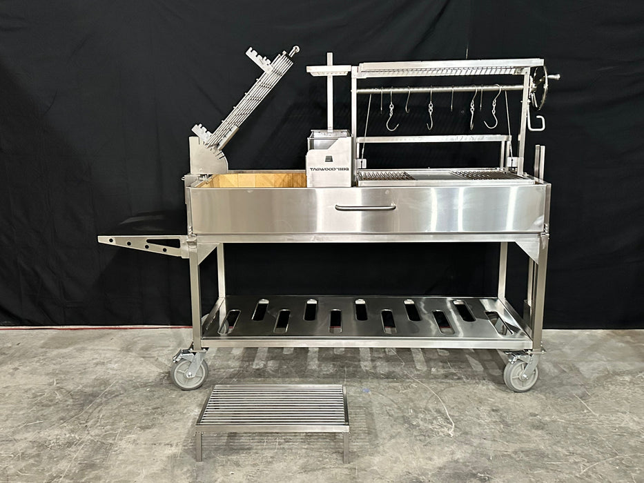 Stono Outdoor Living The Tagwood BBQ Argentine Santa Maria Wood Fire & Charcoal Grill - BBQ26SS by Tagwood BBQ, made of 304 stainless steel, features racks, hooks, a crank system, and wheels. Some parts are detached and shown nearby on a plain black backdrop over concrete.