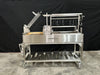 Stono Outdoor Living The Tagwood BBQ Argentine Santa Maria Wood Fire & Charcoal Grill (BBQ26SS) features 304 stainless steel, a side firebox, adjustable grilling racks, hanging hooks, lower storage shelf, and wheels for mobility; shown on concrete with a black backdrop.
