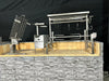 Stono Outdoor Living The Tagwood BBQ Basement Grill - BBQ94SS by Tagwood BBQ features SS 304 stainless steel racks, spits, and hooks on a stone base with a tiled interior and sleek black background, ideal for an authentic basement-style barbecue.