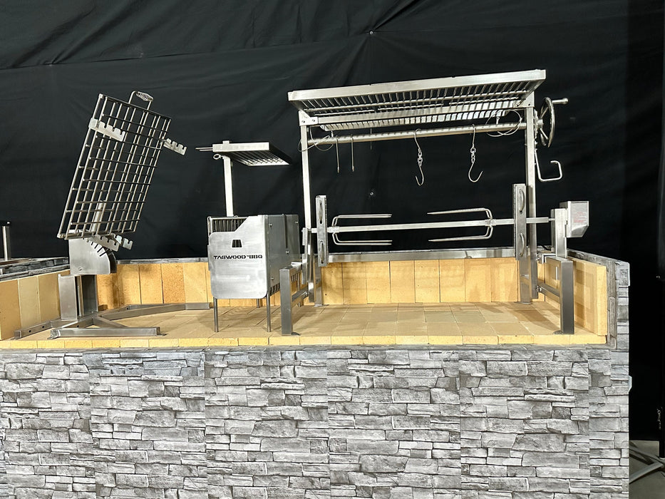Stono Outdoor Living The Tagwood BBQ Basement Grill - BBQ94SS by Tagwood BBQ features SS 304 stainless steel racks, spits, and hooks on a stone base with a tiled interior and sleek black background, ideal for an authentic basement-style barbecue.