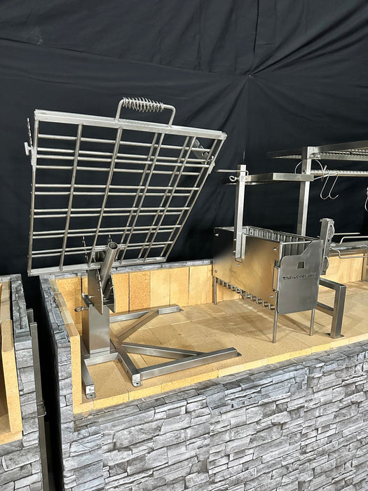 Stono Outdoor Living The Tagwood BBQ Basement Grill - BBQ94SS by Tagwood BBQ features a SS 304 Clamp Grill with large adjustable grate and rotisserie frame on a brick and stone base, perfect for basement gatherings and set against a sleek black backdrop.