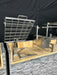Stono Outdoor Living The Tagwood BBQ Basement Grill - BBQ94SS by Tagwood BBQ features a SS 304 Clamp Grill with large adjustable grate and rotisserie frame on a brick and stone base, perfect for basement gatherings and set against a sleek black backdrop.