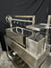 Stono Outdoor Living The Tagwood BBQ Large Top Lid - BBQ59SS by Tagwood BBQ is a stainless steel grill and smoker with a large lid, hooks, shelves, multiple compartments, modern industrial design, main grilling grate, and wheels for easy mobility against a black backdrop.