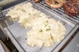 Stono Outdoor Living Shredded potatoes with rosemary cook on the Tagwood BBQ Interchangeable Griddle for BBQ03SS/05SS - BBQ58SS, alongside sausages and roasted meat, making a delicious feast across the grilling surface.