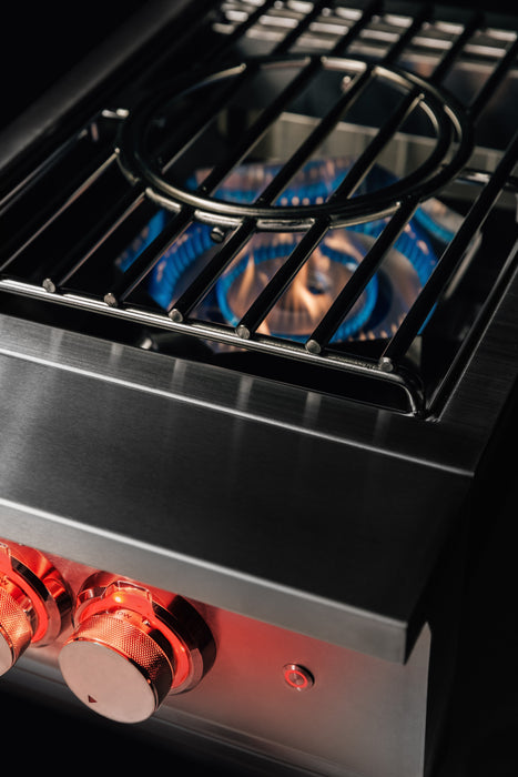 Stono Outdoor Living Close-up of the TrueFlame Natural Gas Power Burner - TFPB by TrueFlame, featuring high BTU side burners, two red-lit control knobs, and blue flames under a cast iron grate—ideal for outdoor kitchens.