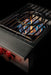Stono Outdoor Living A close-up of the TrueFlame Natural Gas Power Burner - TFPB by TrueFlame showcases high BTU blue and orange flames, metal grates, and two red control knobs—ideal for outdoor kitchens—all set against a black background.