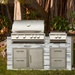 Stono Outdoor Living The Blaze Premium LTE+ 32" 4-Burner Propane Grill with rear infrared burner and grill lights by Blaze is built into a stone counter with storage drawers, set among green plants and trees in a tranquil garden.