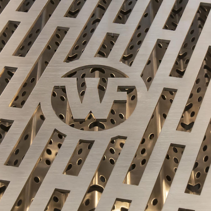 Stono Outdoor Living Close-up of a metallic surface with geometric slits and a stylized W in a circular cutout, showcasing the premium design of Wildfire Outdoor Living’s Ranch Pro 36-in 3 Burner Black 304 SS Natural Gas Grill (WFPRO36G-BSS-NG).