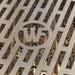 Stono Outdoor Living Close-up of a metallic surface with geometric slits and a stylized W in a circular cutout, showcasing the premium design of Wildfire Outdoor Living’s Ranch Pro 36-in 3 Burner Black 304 SS Natural Gas Grill (WFPRO36G-BSS-NG).