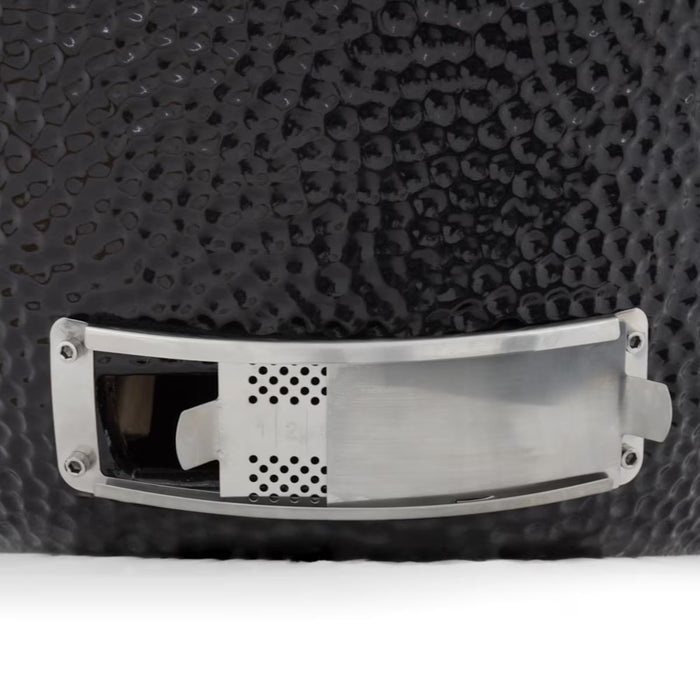 Stono Outdoor Living Close-up of the stainless steel vent on the Coyote Asado Smoker, Built-In - C1CHCS by Coyote, shown on a textured black surface. This feature allows for precise temperature control during outdoor cooking.
