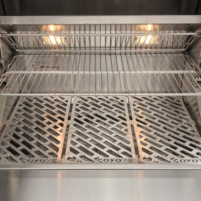 Stono Outdoor Living Close-up of the Coyote 28" Pellet Grill (C2P28) shows stainless steel interior with metal grates and upper wire rack, both lit by two built-in lights for precise outdoor cooking.