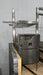 Stono Outdoor Living The Tagwood BBQ Height Adjustable Secondary Grate for the BBQ09SS Grill, model BBQ96SS, by Tagwood BBQ features an adjustable rack and metal rods, designed for a stone counter setup against a light gray wall.
