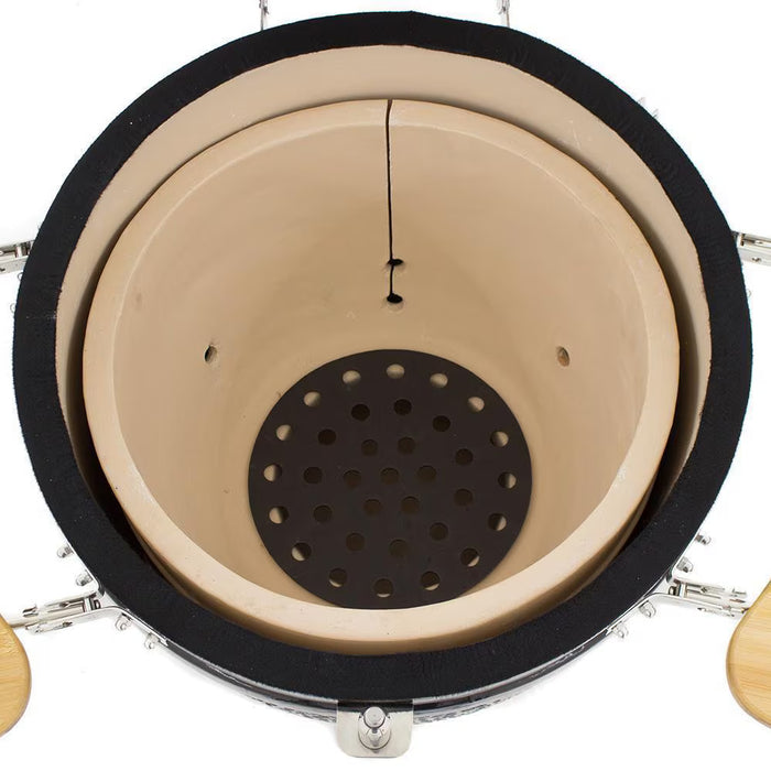 Stono Outdoor Living Top view of a Coyote Asado Smoker w/ Stand & Side Shelves (C1CHCS-FS) showing beige ceramic interior, a circular perforated grate, black insulation edge, silver metal fasteners, and wooden side handles. Brand: Coyote.