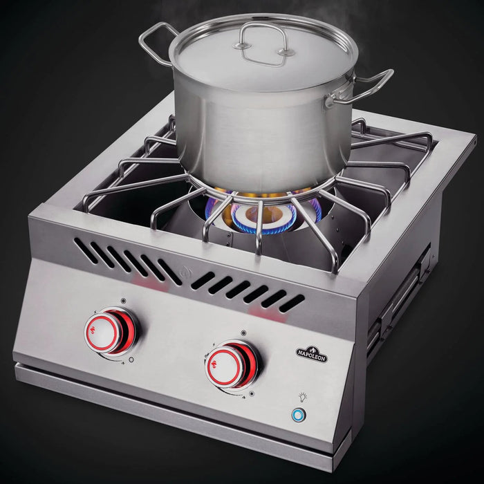 Stono Outdoor Living A stainless steel pot with a lid sits on the Napoleon Built-In 700 Series Propane Gas Power Burner (BIB18PBPSS), which features two red knobs and a blue flame, as steam rises from the pot.