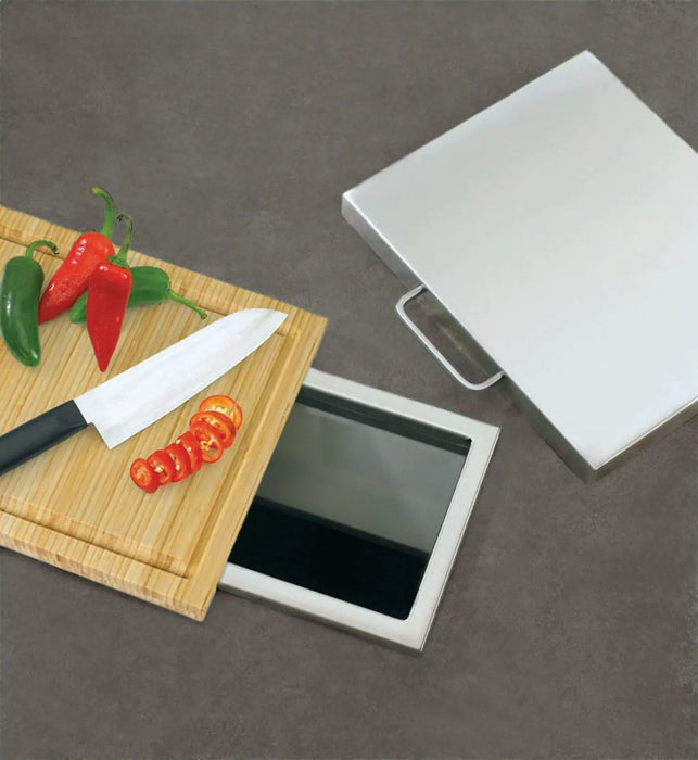 Stono Outdoor Living A Twin Eagles Trash Chute with Cutting Board (TETC) holds sliced tomatoes, whole jalapeños, a red chili, and a knife on its board, while its open compartment offers convenient outdoor storage.