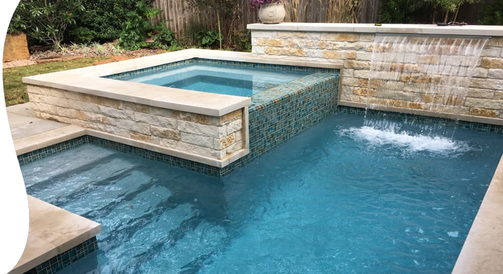 Custom Blue Haven pool with raised square spa and cascading water feature.